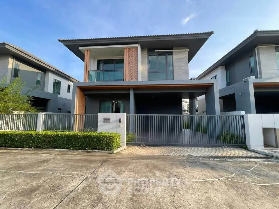Modern two-story house with sleek design and spacious driveway in a suburban neighborhood.