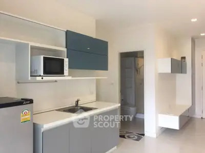 Modern kitchen with sleek cabinetry and built-in microwave in a stylish apartment.