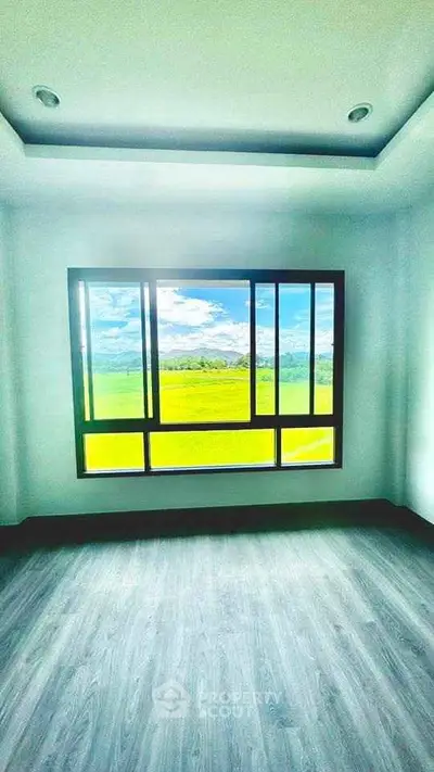 Bright room with large window offering stunning countryside view, perfect for serene living.