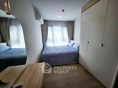 Modern bedroom with large mirror and ample natural light in a stylish apartment.