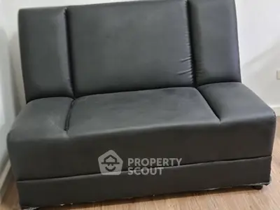Modern black sofa in a stylish living room setting with wooden flooring.
