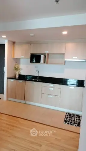 Modern kitchen with sleek cabinetry and built-in microwave in a stylish apartment.