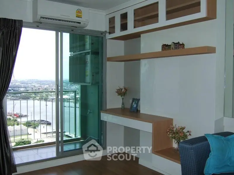 Modern living room with balcony and river view, featuring built-in shelves and air conditioning.