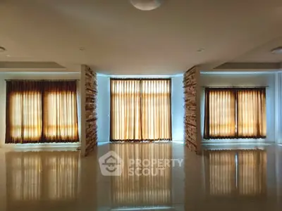 Spacious living room with elegant floor-to-ceiling windows and warm natural lighting.