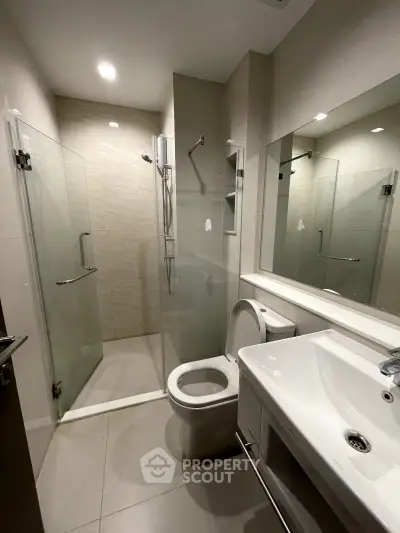 Modern bathroom with glass shower and sleek fixtures in contemporary apartment.