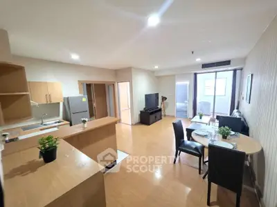 Spacious open-layout living room with modern kitchen and dining area, featuring sleek wooden flooring and natural light.