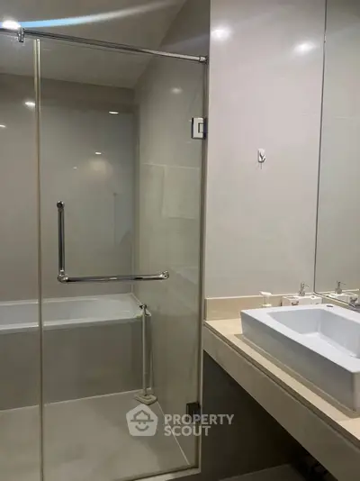 Modern bathroom with glass shower and sleek sink design.