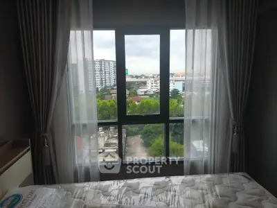 Bright bedroom with large window offering city view and lush greenery