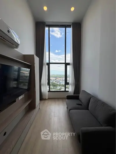 Modern living room with floor-to-ceiling window offering stunning city and sea views.