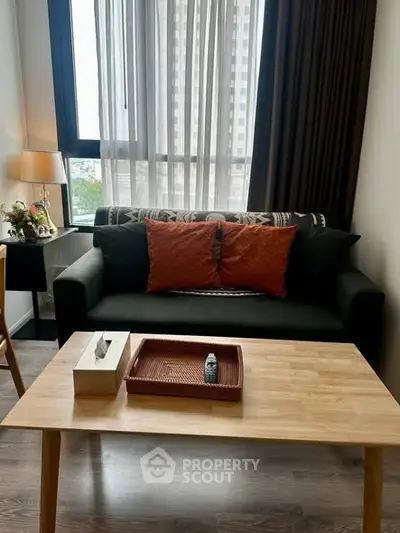 Cozy living room with modern sofa and wooden coffee table, featuring large window with city view.