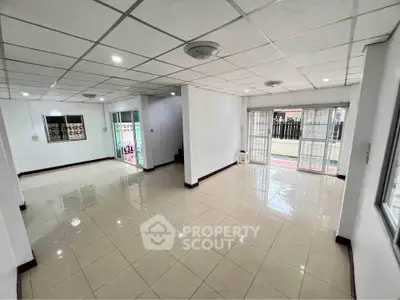 Spacious open-plan living room with tiled flooring and ample natural light.