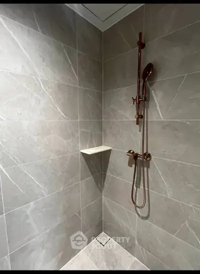 Modern bathroom shower with sleek gray tiles and elegant fixtures.