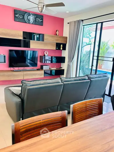 Modern living room with sleek furniture and large glass doors leading to a balcony with a pool view.
