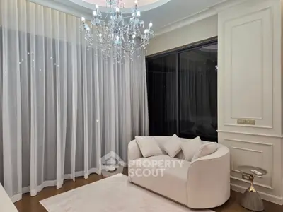 Elegant living room with chandelier and modern sofa, featuring floor-to-ceiling curtains.