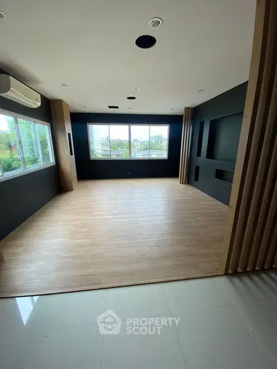 Spacious modern room with large windows and wooden flooring, ideal for versatile use.