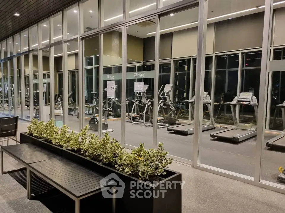 Modern gym with large glass windows and state-of-the-art equipment in a luxury residential building.