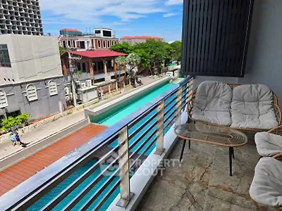 Spacious balcony with seating overlooking a vibrant cityscape and pool view.