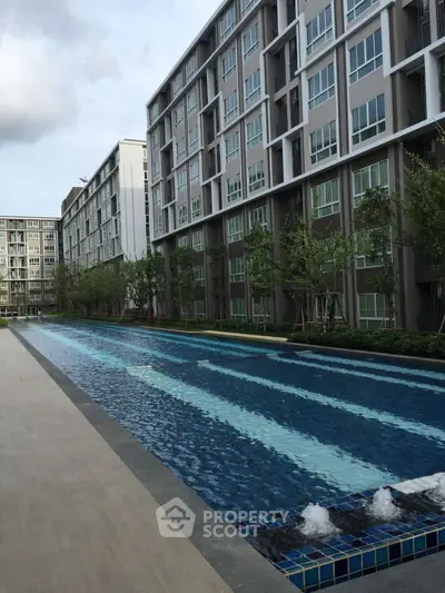 Modern condominium with a long swimming pool and lush greenery, perfect for luxury living.