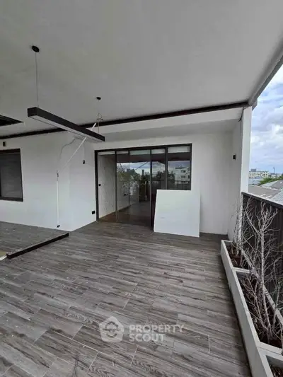 Spacious balcony with modern wood flooring and large sliding glass doors.