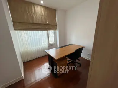 Modern study room with sleek desk and chair, featuring large window with natural light and elegant curtains.
