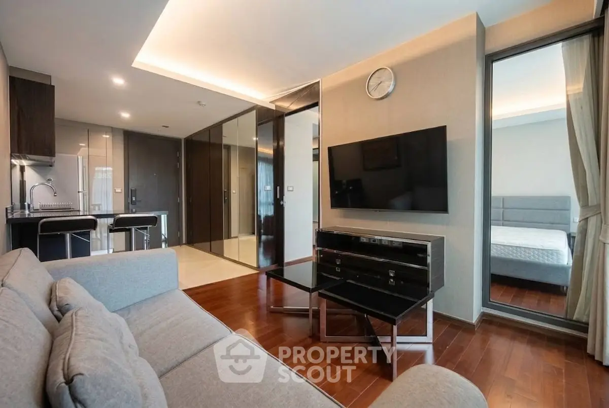 Modern living room with sleek furniture and open kitchen layout in luxury apartment.
