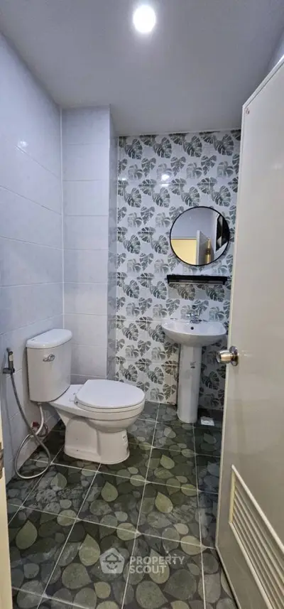 Modern bathroom with leaf-patterned tiles and round mirror