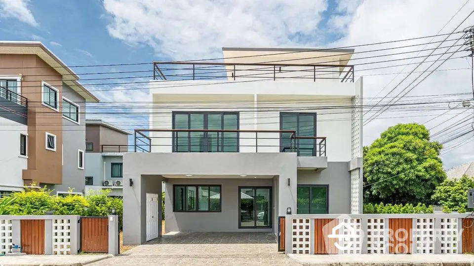 Modern two-story house with spacious balcony and sleek design in a suburban neighborhood.