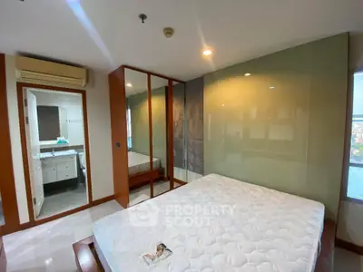Spacious bedroom with mirrored closet and ensuite bathroom in modern apartment