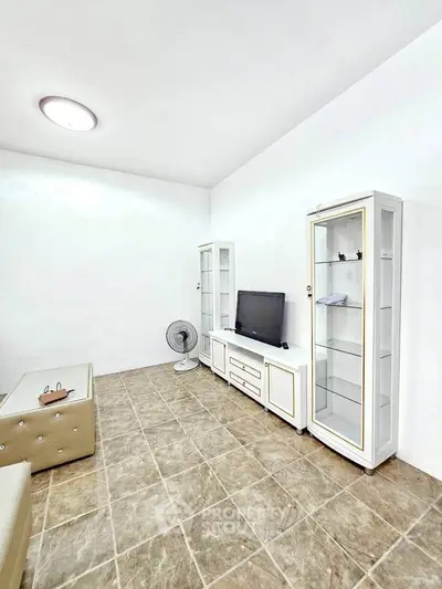 Spacious living room with modern furniture and tiled flooring, perfect for relaxation and entertainment.