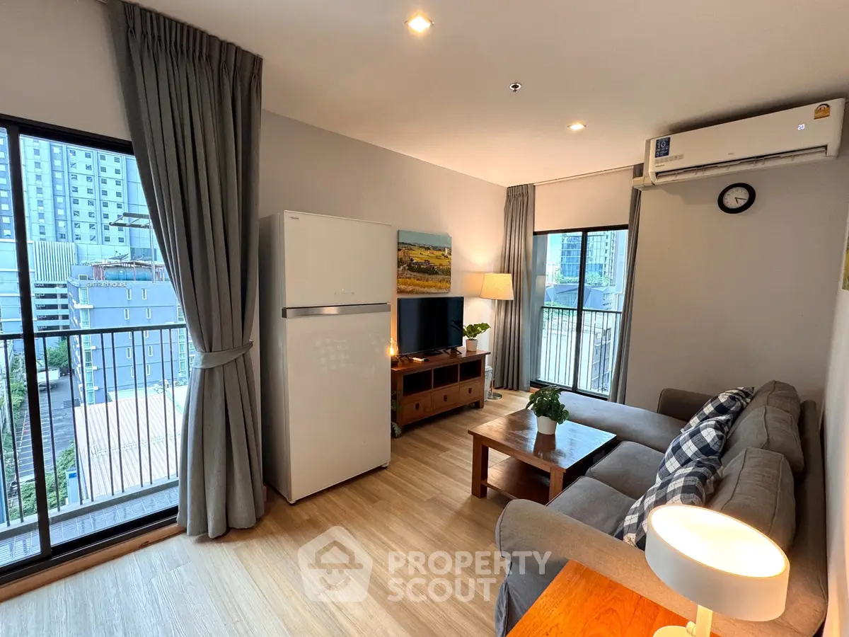 Modern living room with balcony view, featuring cozy sofa, wooden furniture, and natural light.