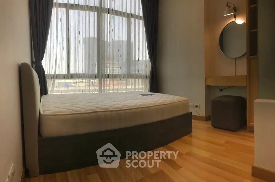 Modern bedroom with large window and stylish furniture in urban apartment