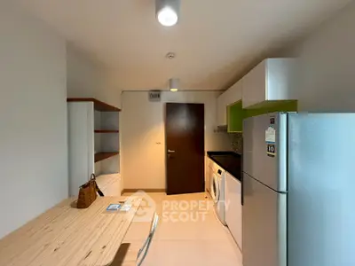 Modern kitchen with sleek appliances and wooden dining table in a stylish apartment.