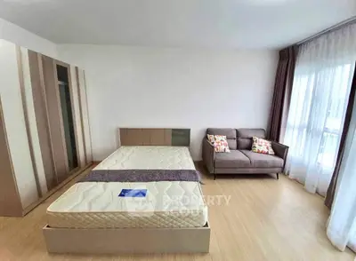 Spacious bedroom with modern decor and large window for natural light.