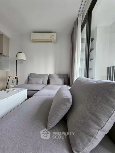 Modern living room with sleek gray sofa and large windows for natural light.