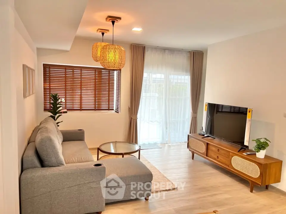 Modern living room with stylish decor, featuring a cozy gray sofa, wooden TV stand, and elegant lighting.