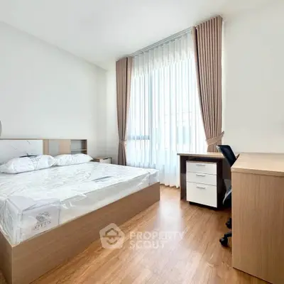 Bright and airy bedroom with modern furnishings and large window in a stylish apartment.
