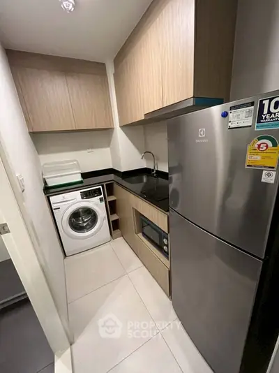 Modern compact kitchen with washing machine and fridge in sleek apartment
