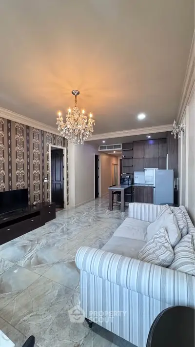Luxurious living room with elegant chandelier and modern kitchen in open layout apartment.