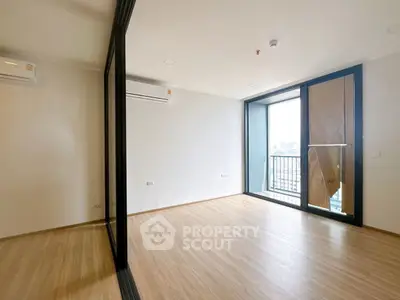 Spacious modern room with large window and balcony view in urban apartment.