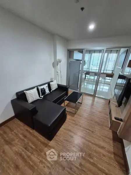 Modern living room with sleek furniture and large windows offering city views.