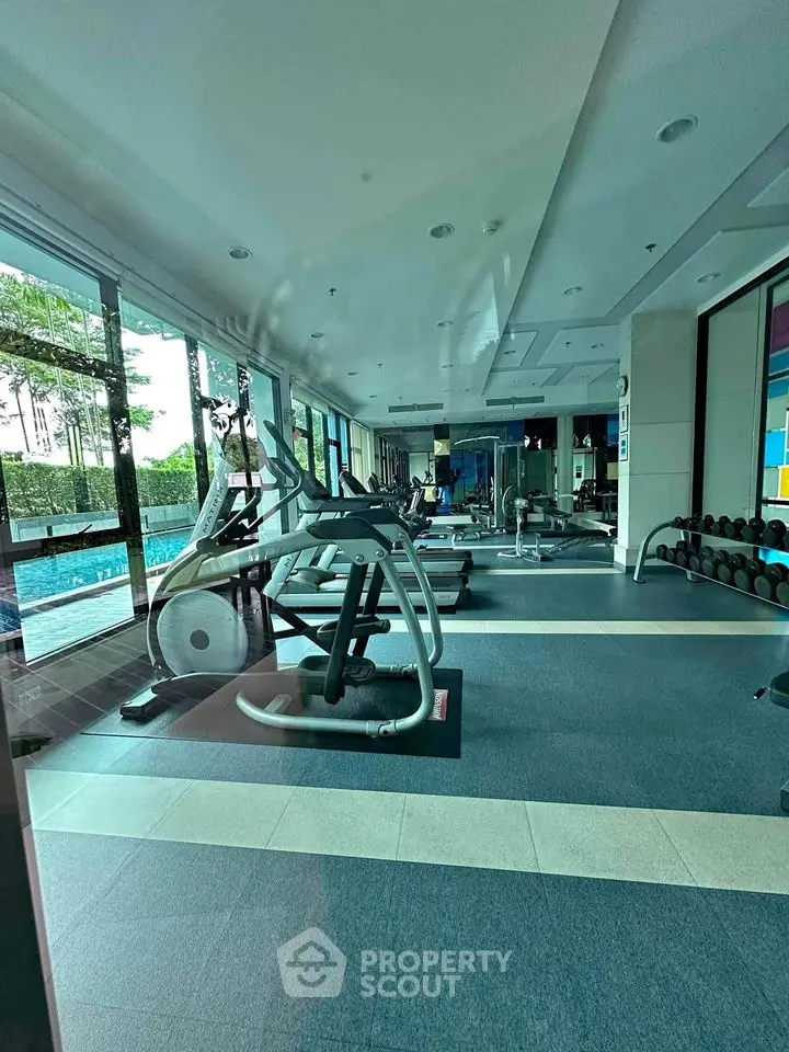Modern gym with state-of-the-art equipment and pool view in luxury residential complex.