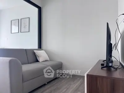 Modern living room with sleek gray sofa and wall-mounted TV, perfect for cozy relaxation.