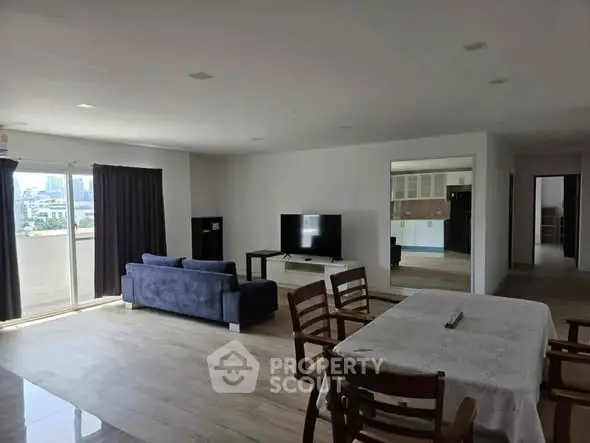 Spacious open-plan living room with modern decor and city view balcony.