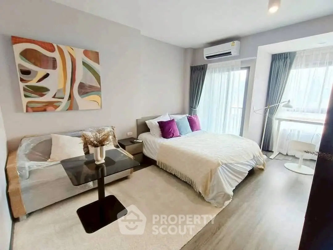 Modern bedroom with stylish decor and natural light, featuring a cozy bed and seating area.