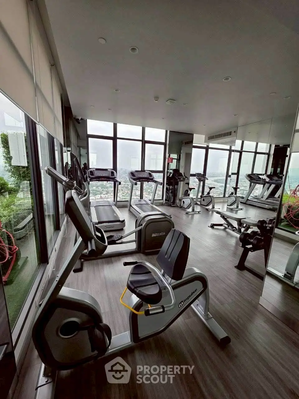 Modern gym with city view, featuring state-of-the-art exercise equipment and floor-to-ceiling windows.