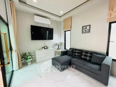 Modern living room with sleek design, featuring a cozy gray sofa, wall-mounted TV, and elegant decor.
