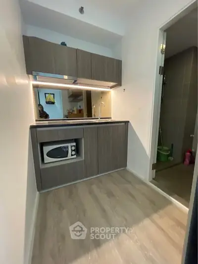 Compact modern kitchen with sleek cabinetry and built-in microwave