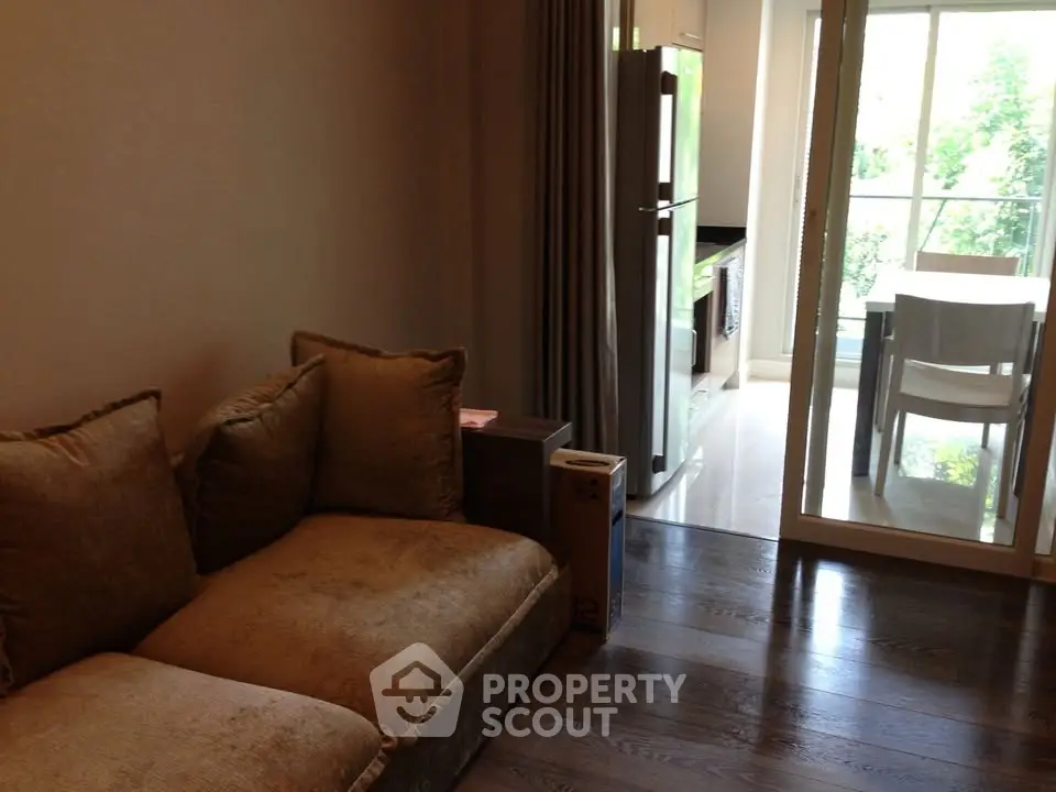 Cozy living room with plush sofa and view into modern kitchen and dining area with natural light.