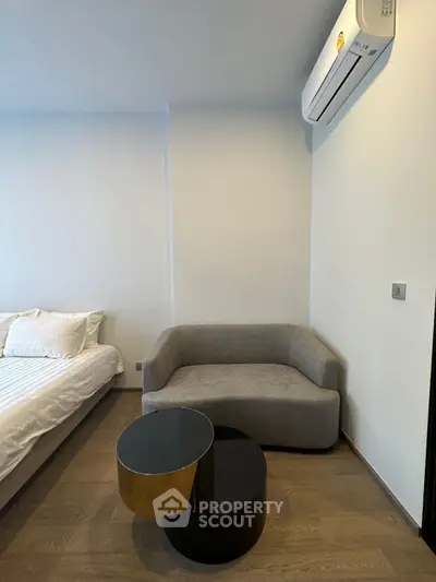 Modern bedroom with stylish sofa and air conditioning, featuring minimalist design and cozy ambiance.
