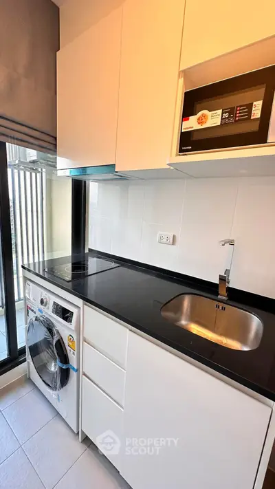 Modern kitchen with sleek appliances and ample storage in a stylish apartment.